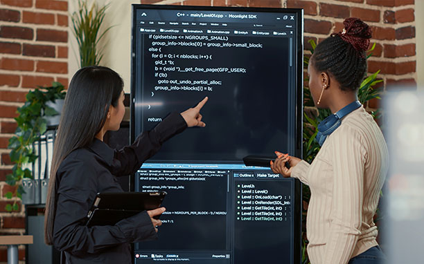 Duas mulher trabalhando em frente a um monitor vertical para resolver um problema de app crash.