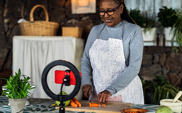 Mulher negra cortando legumes, grava vídeo para postar em um app de sucesso.